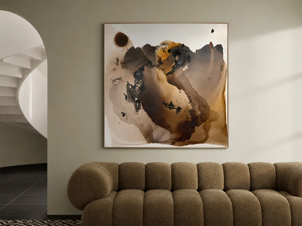 Sun Up by Conchita Carambano, umber and amber abstract painting shown above a lounge